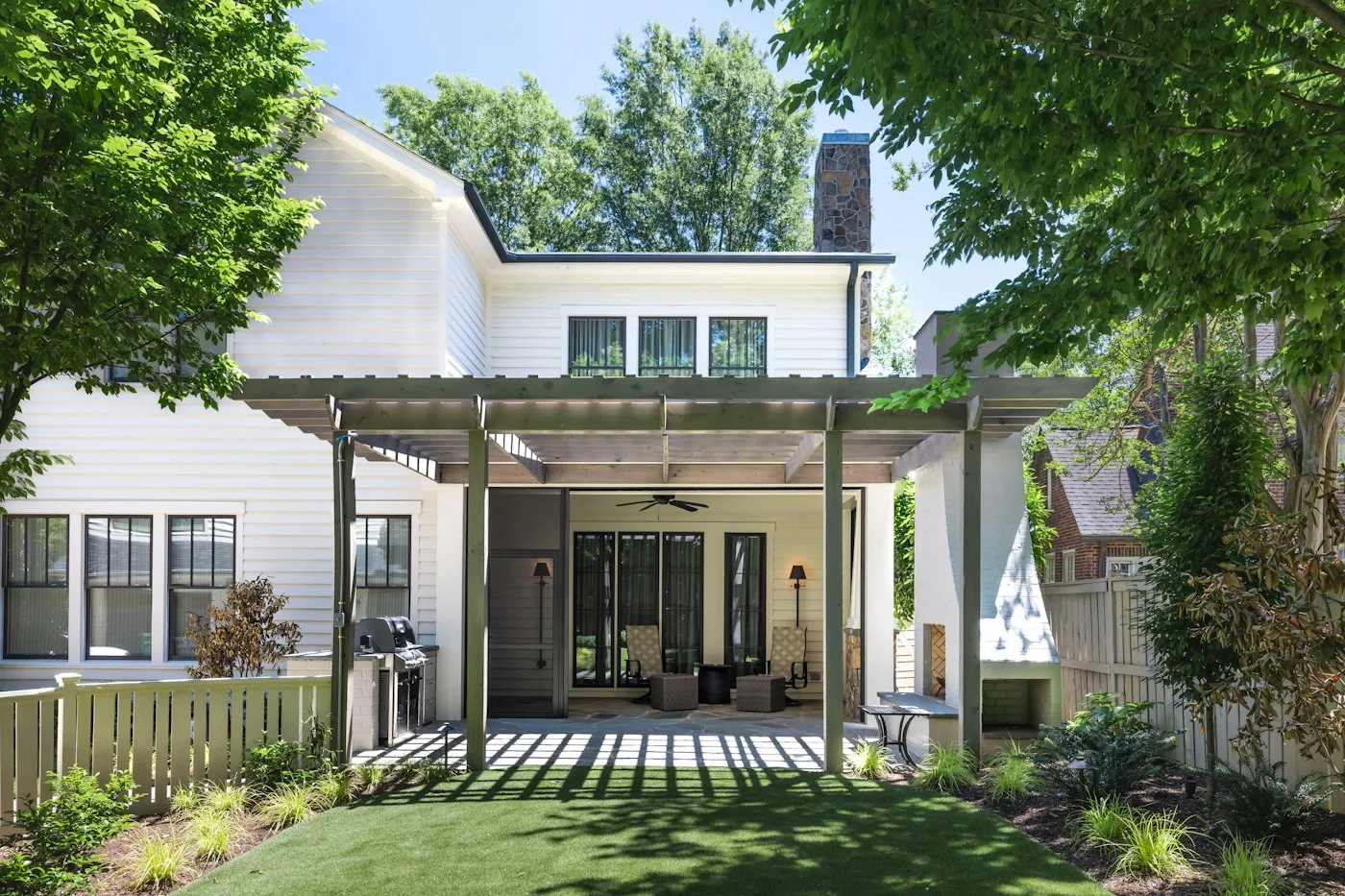 White home with a covered patio, roof gutters and landscaped yard