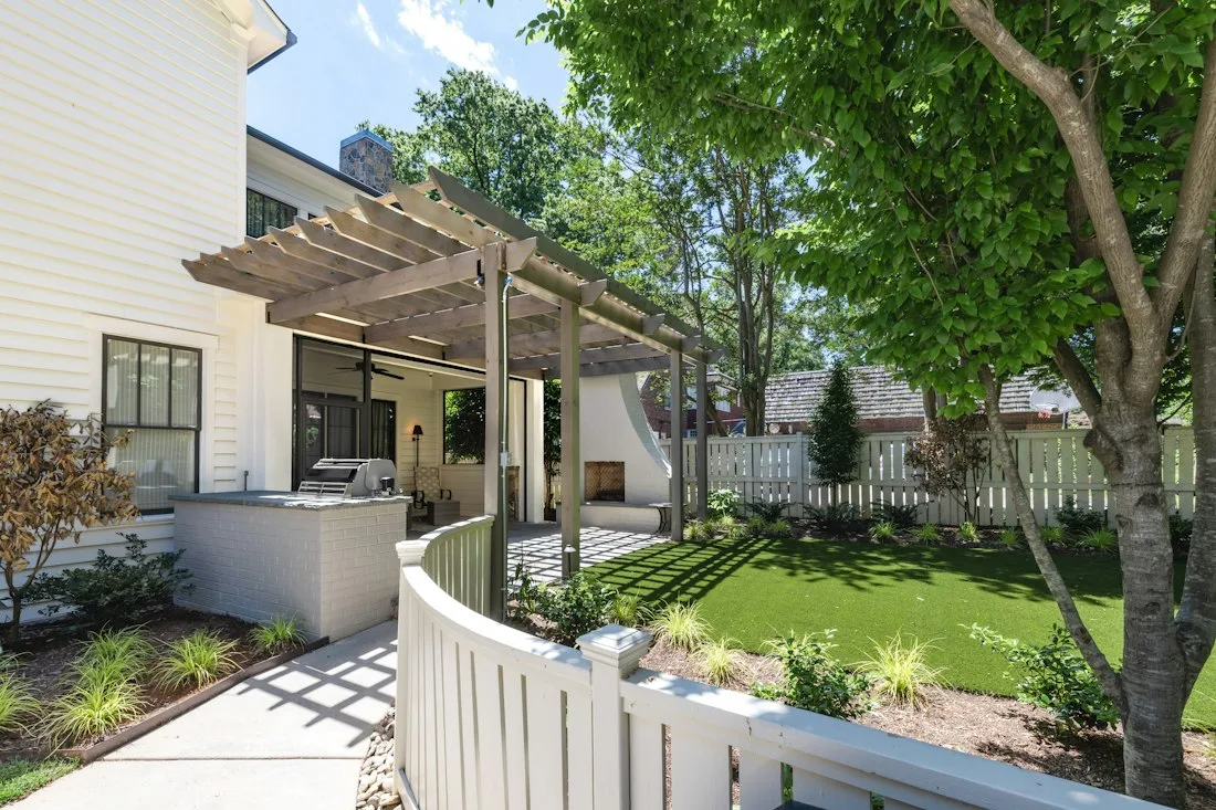 Landscaped backyard with a pergola, patio and green lawn