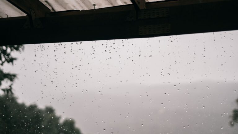 Why Gutters Overflow in Heavy Rain (Even When They Look Clean) Raindrops on a house roof during heavy rain, where gutter overflow begins at the roof edge