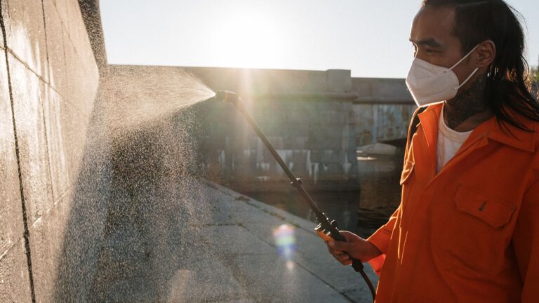 Soft Washing vs. Pressure Washing: Which Surfaces Need Each? Spraying water onto an outdoor wall during exterior cleaning