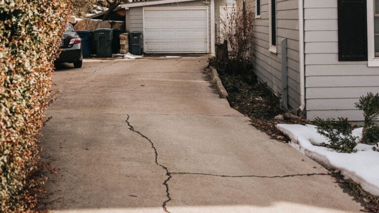 Cracked concrete residential driveway leading to a garage