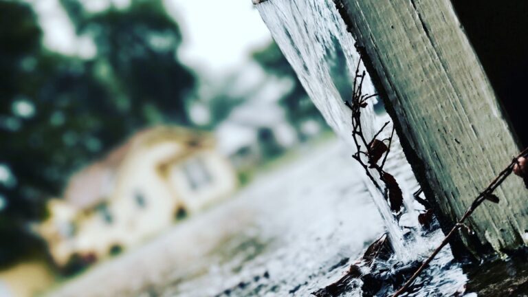 Rainwater pouring from a house gutter during a heavy storm