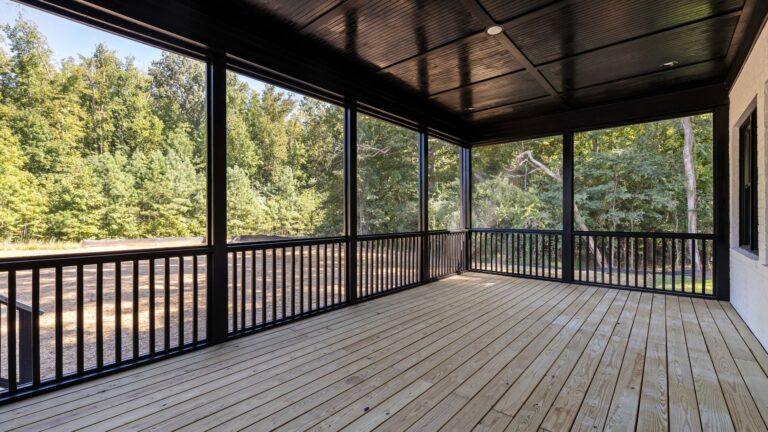 A spacious wooden deck with railing overlooking a forest, boards freshly stained and even in tone