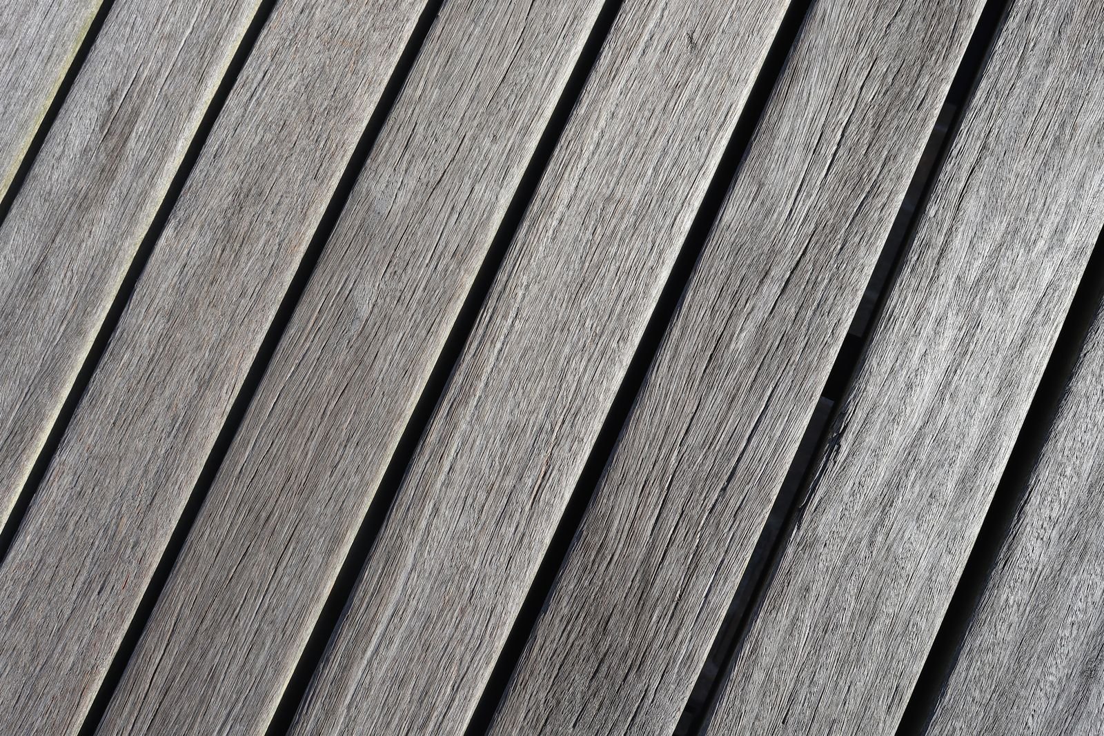 Close-up of weathered gray wooden deck planks showing the silvery tone of sun-damaged wood with no stain protection left