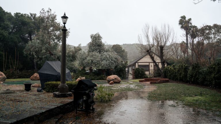 Yard Drainage Problems: Causes of Soggy Ground After Rain Stormy suburban backyard with standing water covering parts of the lawn and patio after rain.