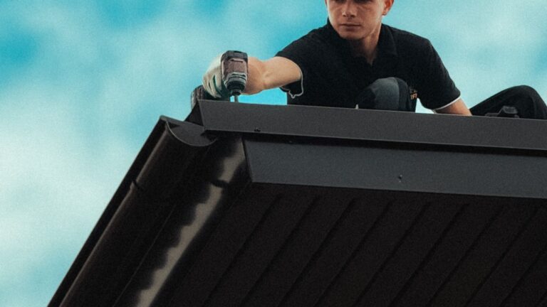 Roofing contractor working along a house roofline under a clear blue sky