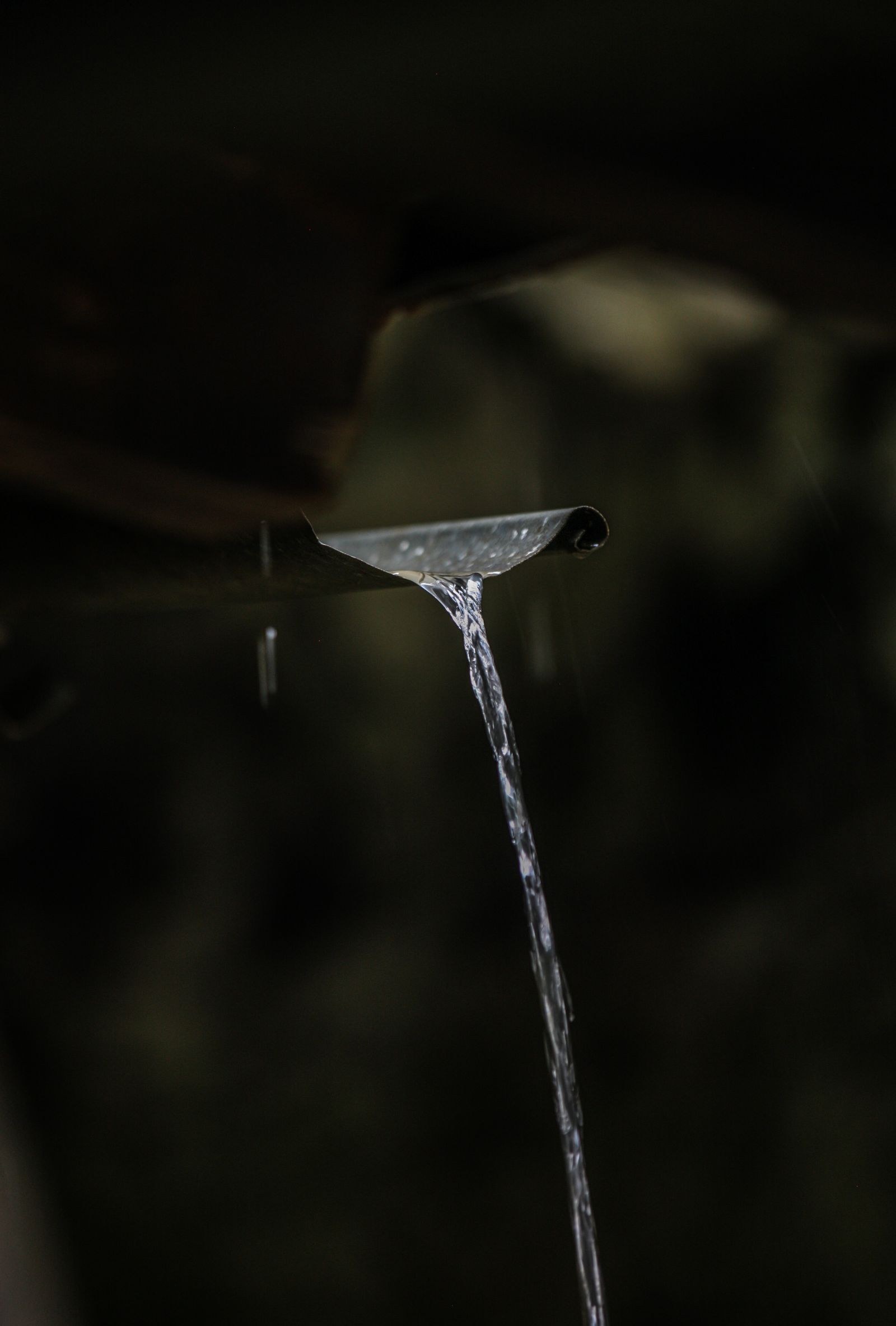 Close-up of rainwater pouring from a house gutter during rainfall