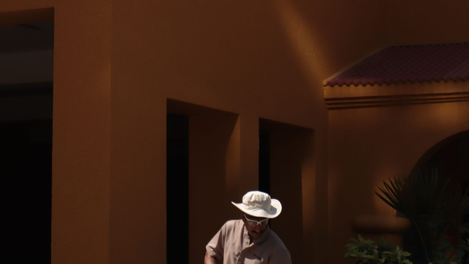 A worker pressure washing a concrete sidewalk, one of the few surfaces that handles high pressure well.