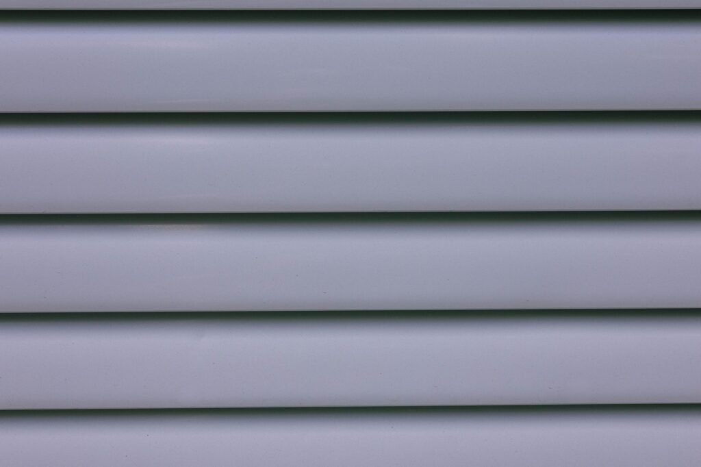 Close-up of gray horizontal vinyl siding panels showing clean layered laps on a finished wall