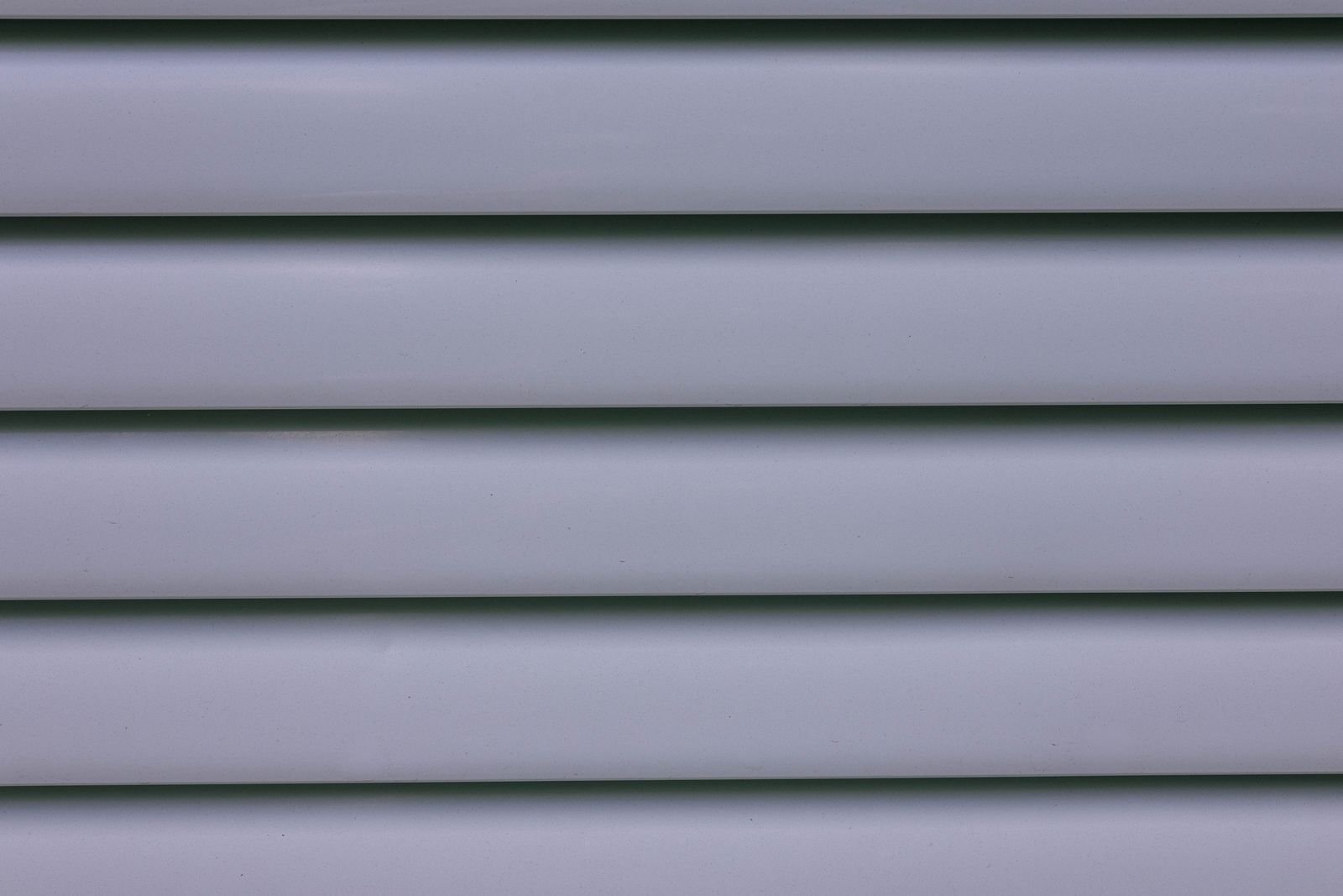 Close-up of gray horizontal lap siding panels showing the lap lines where dirt and grime collect